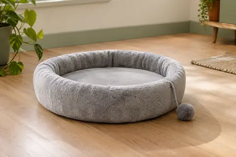 Plateforme ronde en peluche gris clair à rebord rembourré, posée à plat sur le parquet avec sa balle de jeu